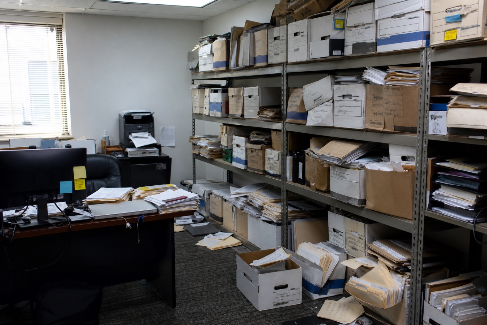 Before: a back office with overflowing boxes, loose files on the floor and a buried desk